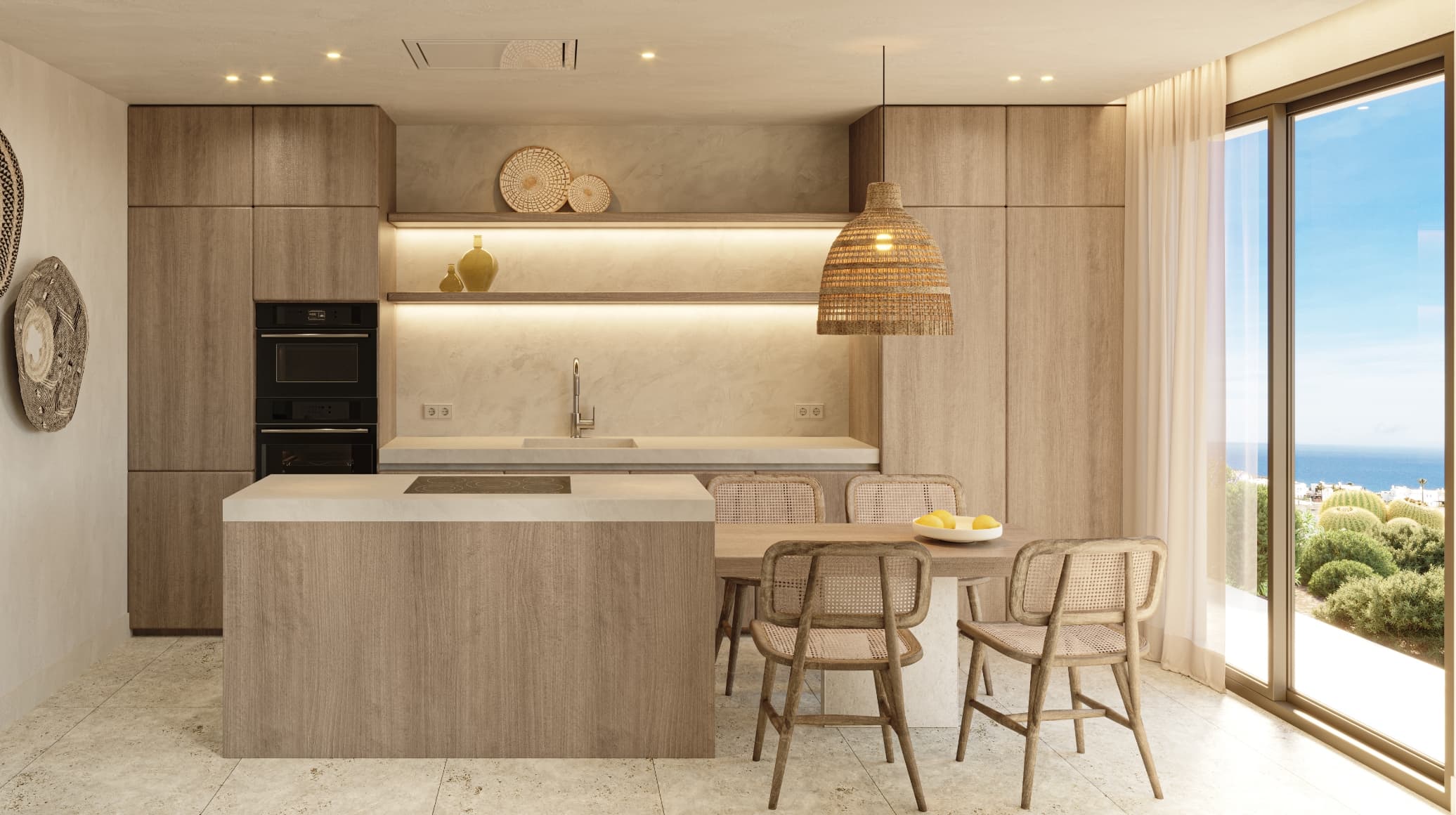 Mediterraneo_cocina-h-1 - MiraCasa Modern open kitchen with wood cabinetry, a central island, and a woven pendant light overlooking a dining area with wicker chairs and a coastal ocean view through large windows.
