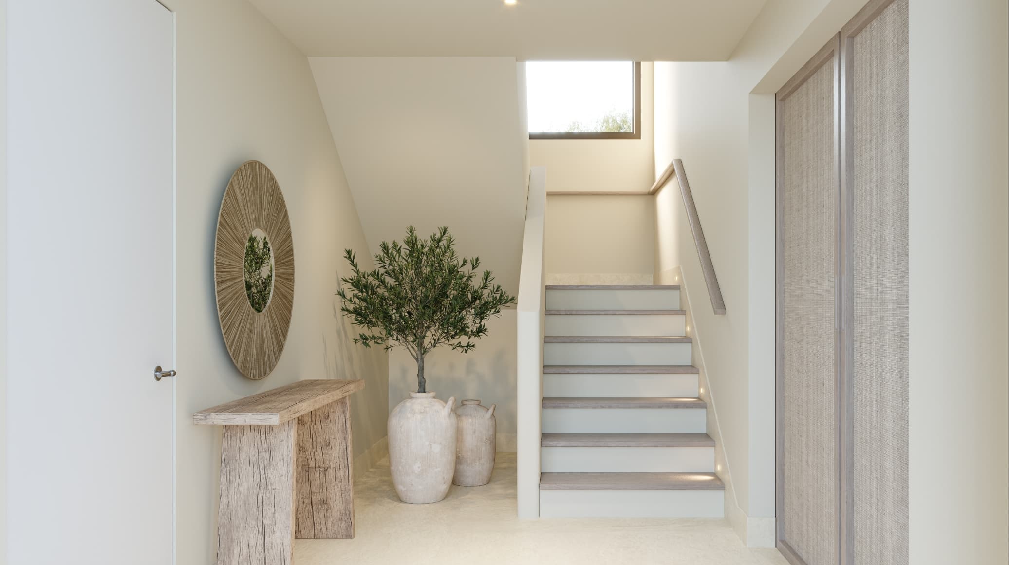 Mediterraneo_entrada - MiraCasa Bright hallway with white walls, a white staircase, a potted olive tree, and a round woven mirror nearby.