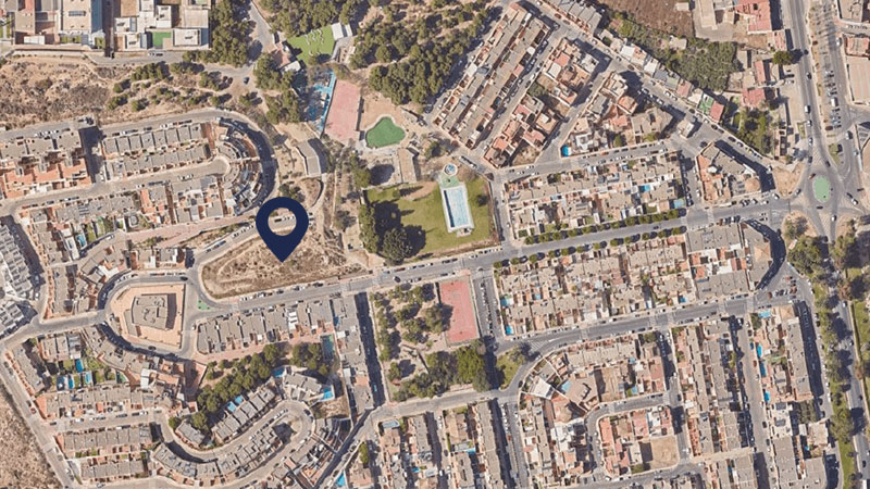 Aerial view of a densely built neighborhood with a blue map pin indicating a target location.