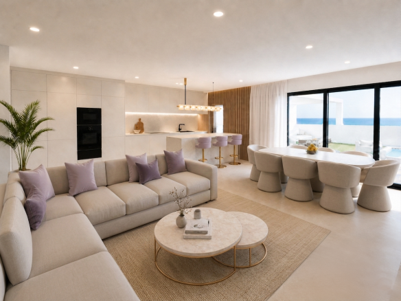 Salón Cocina Comedor - MiraCasa Open-concept living area with beige sectional sofa, lavender cushions, marble coffee tables, and a bright kitchen island overlooking a deck and ocean view.